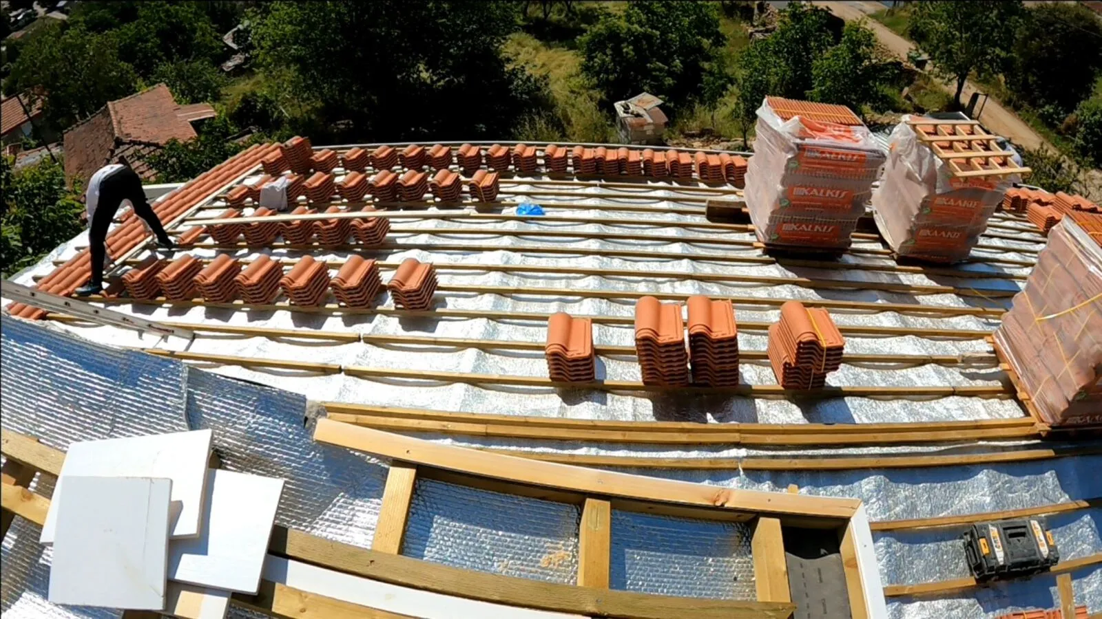 Tile installation in progress, stacks ready, membrane visible beneath