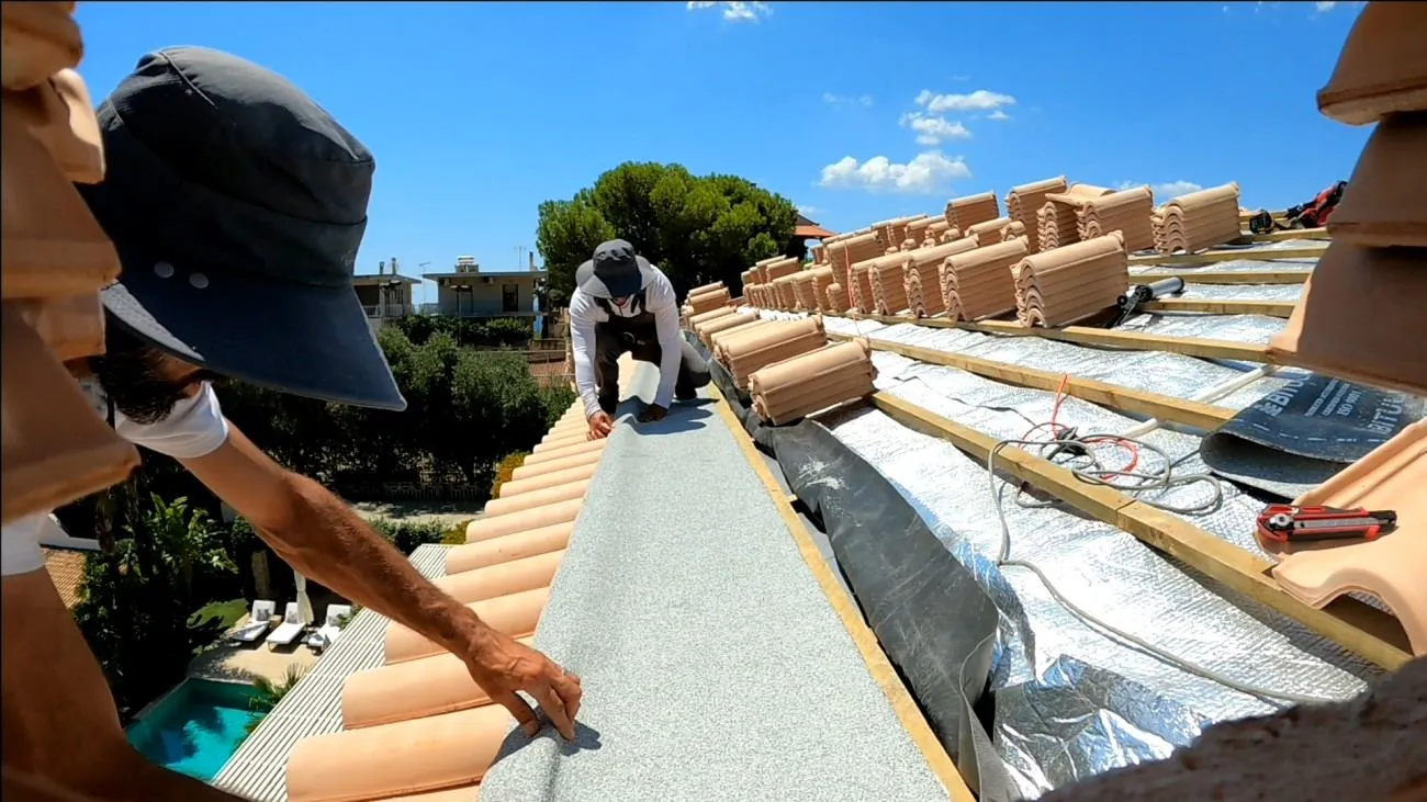 Hidden internal drainage gutter under construction along the roof edge, before the final tile course.
