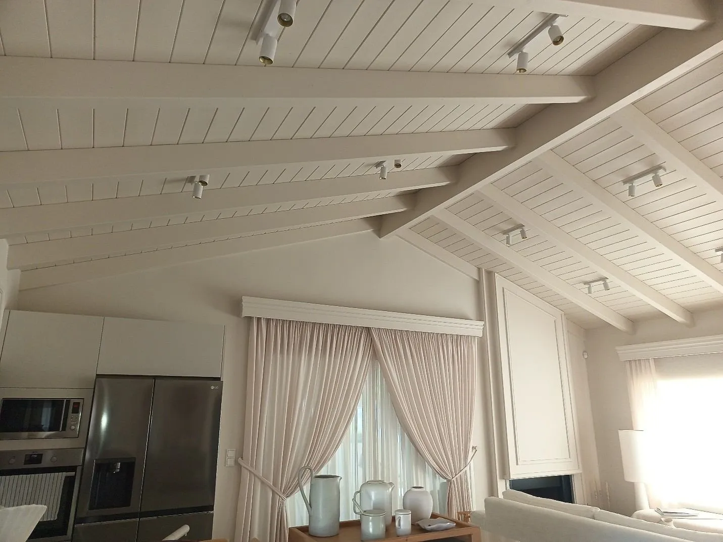 Finished interior. Timber ceiling beams converging on the new raised ridge, family kitchen below.